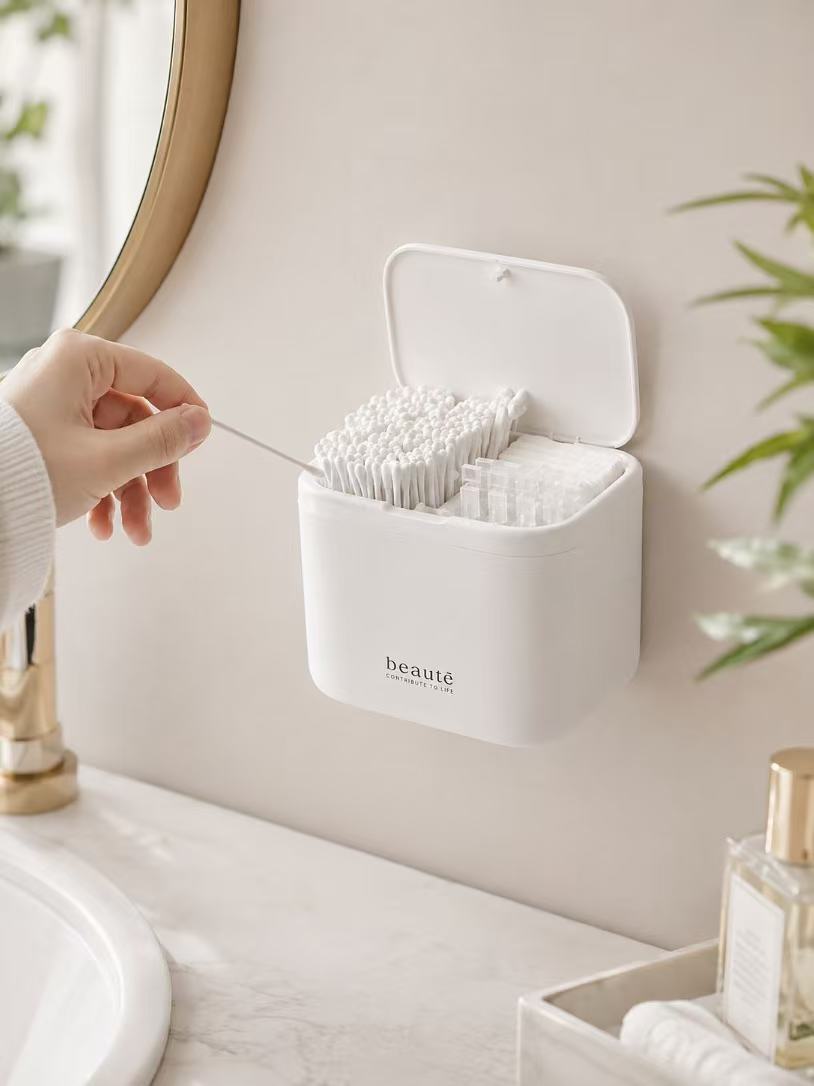 Hand taking a cotton swab from a wall-mounted bathroom organizer