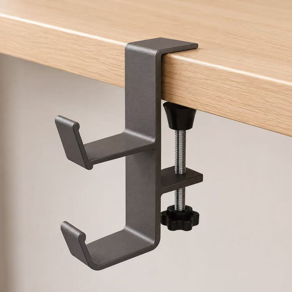 Dual-hook metal desk clamp mounted on a light wood desktop