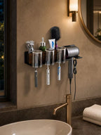 Large black bathroom organizer with four covered toothbrush cups and hair dryer holder in a warm bathroom
